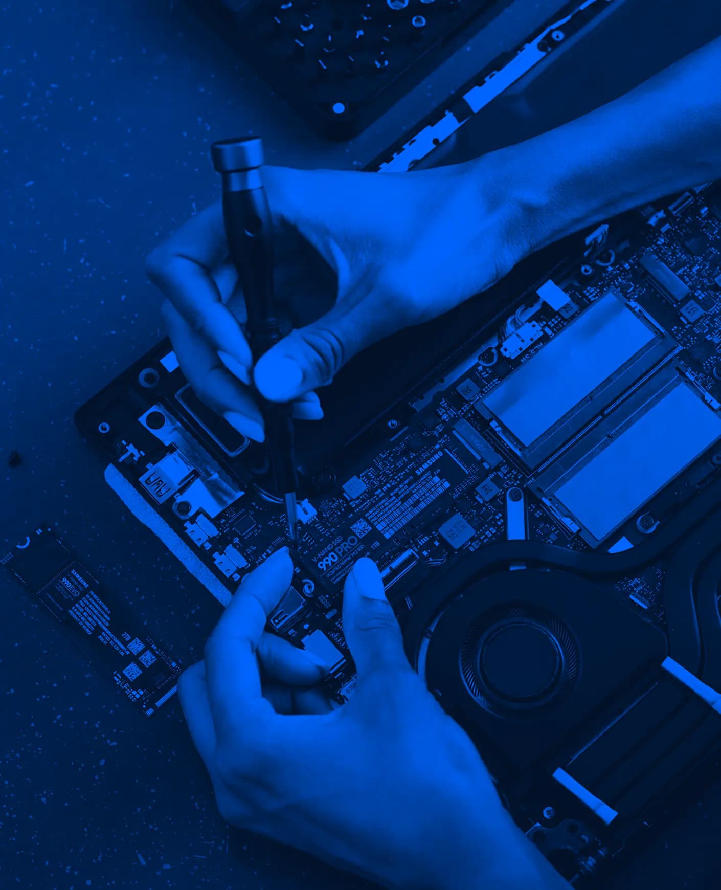 Uma pessoa consertando um laptop com uma chave de fenda.